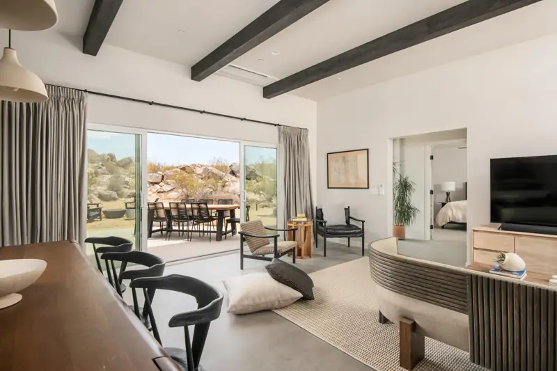 Living room: Stunning views through the wall of windows. The living room features designer furniture pieces and a 65" 4K Sony Smart TV with a Sonos sound bar.